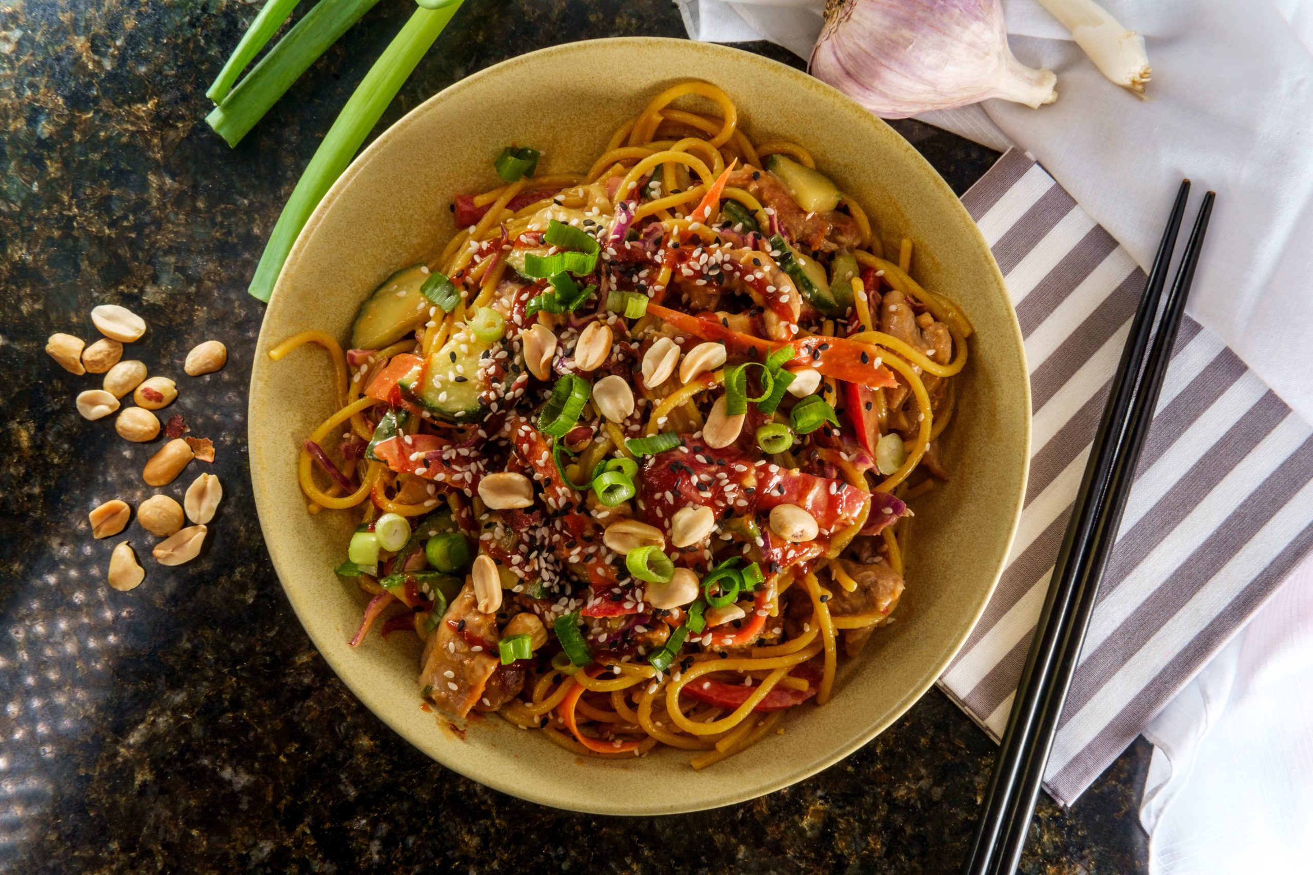 A Bowl Of Noodles Drizzled With Sriracha Sauce